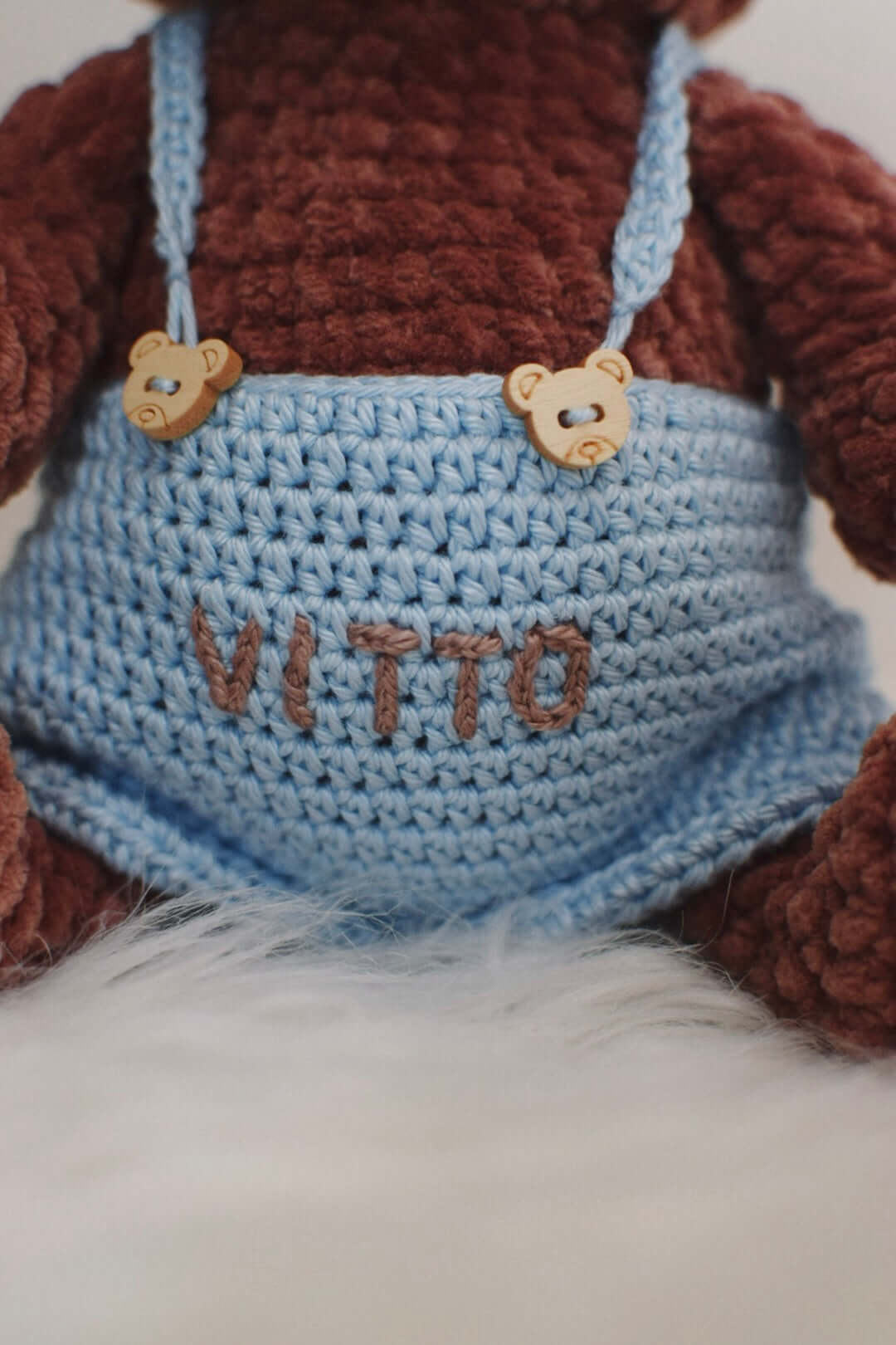 Dettaglio salopette azzurra con ricamo su orsetto marrone 
