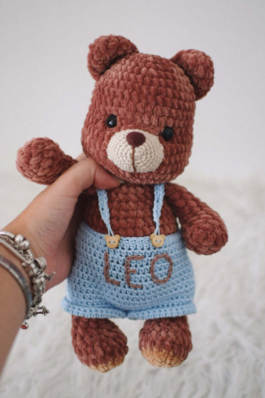 Peluche Orsetto Del Cuore: un orsetto marrone con salopette azzurra, perfetto per coccole e giochi.
